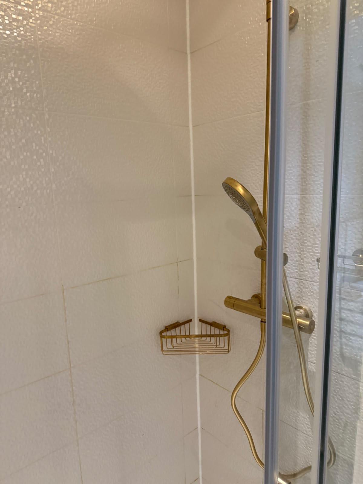 White tiled shower enclosure with a straight silicone line by Blackline Mastic