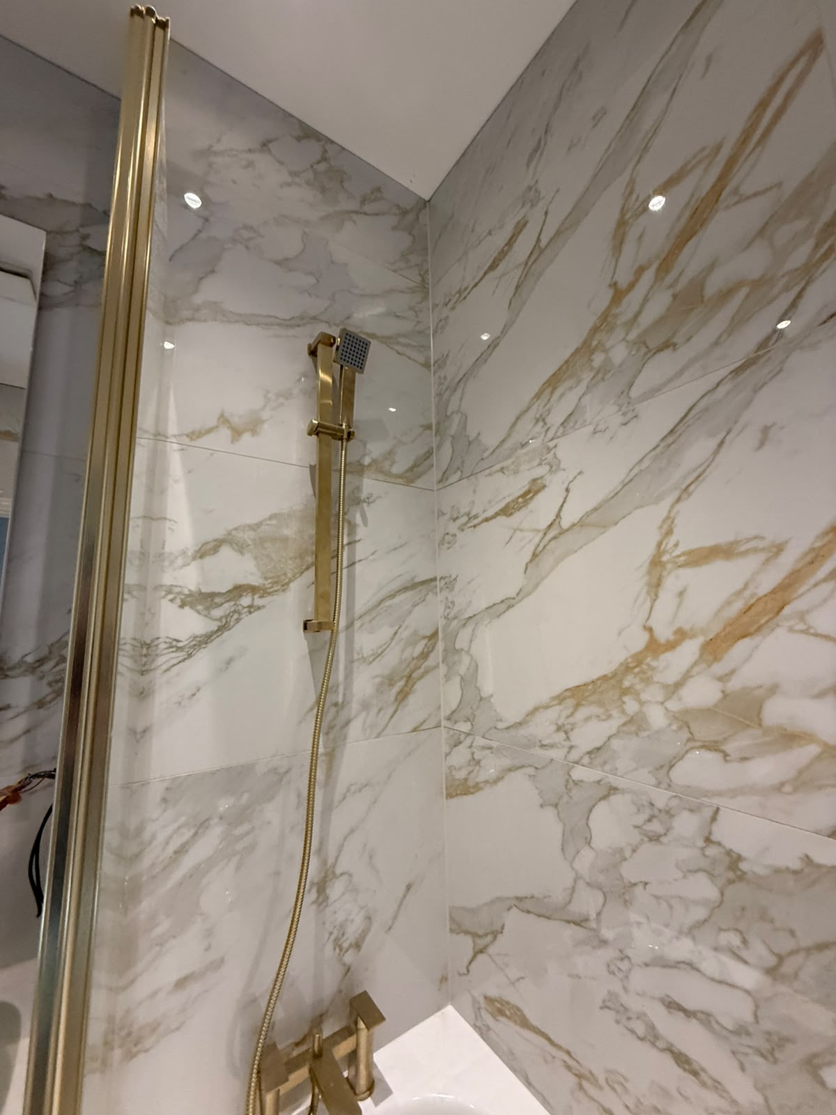 Marble shower wall and fitting joints sealed by Blackline Mastic