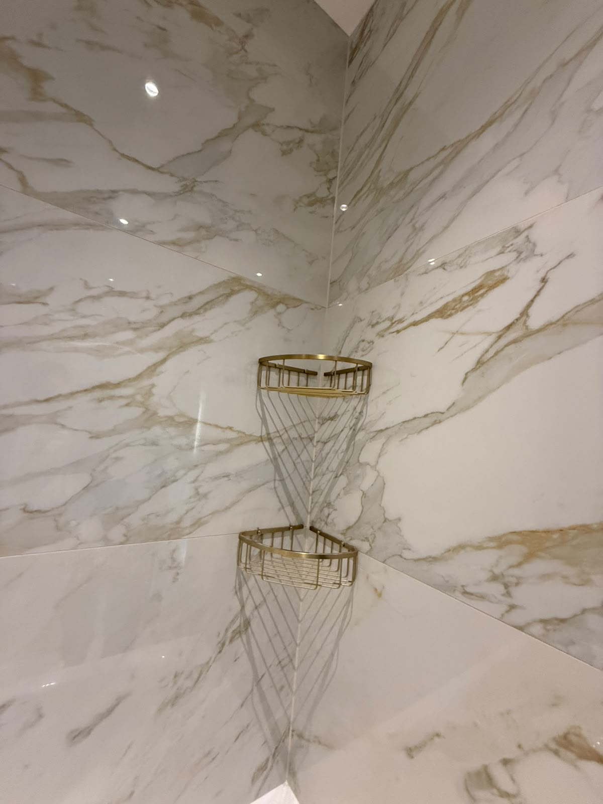 Marble shower corner with brass baskets sealed by Blackline Mastic