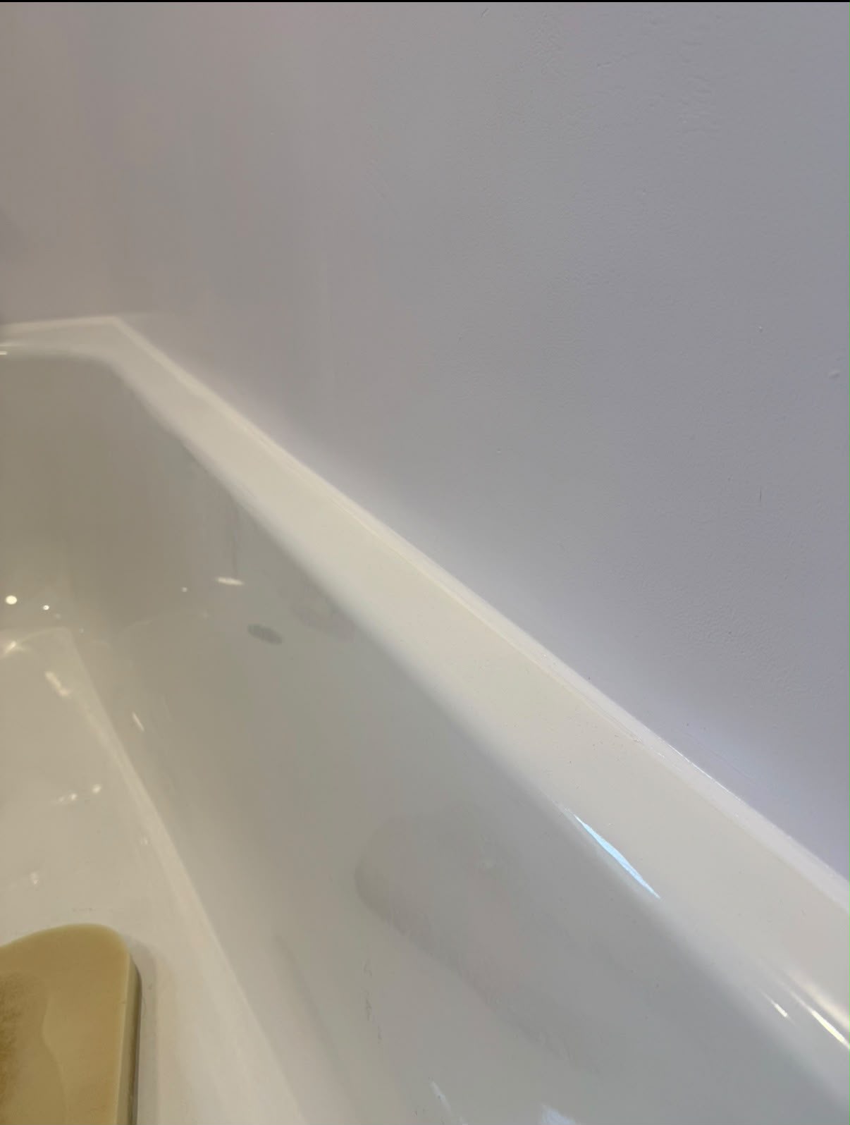 Close view of a clean bath-edge silicone line by Blackline Mastic