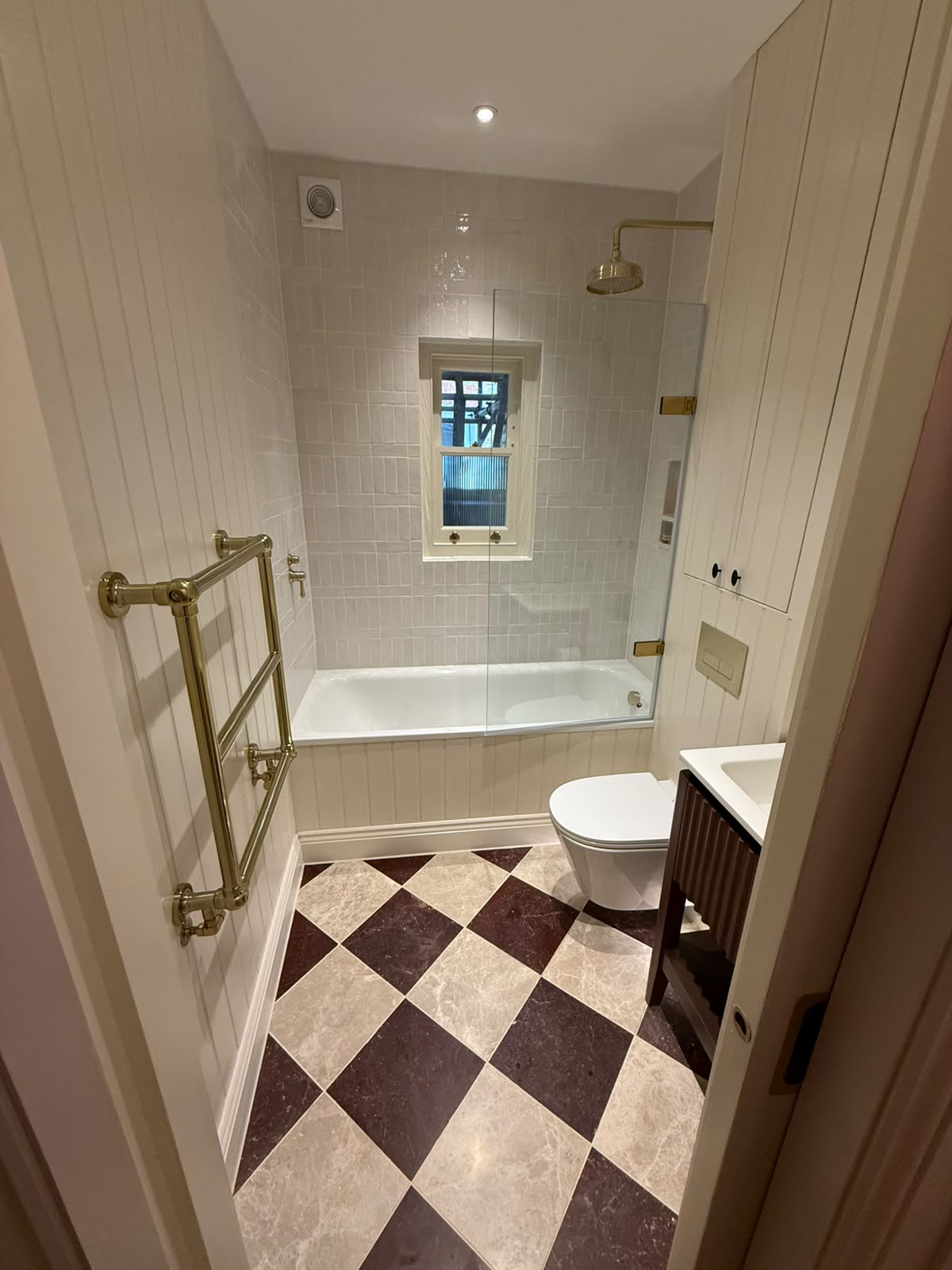 Panelled bathroom with bath screen and marble floor sealed by Blackline Mastic