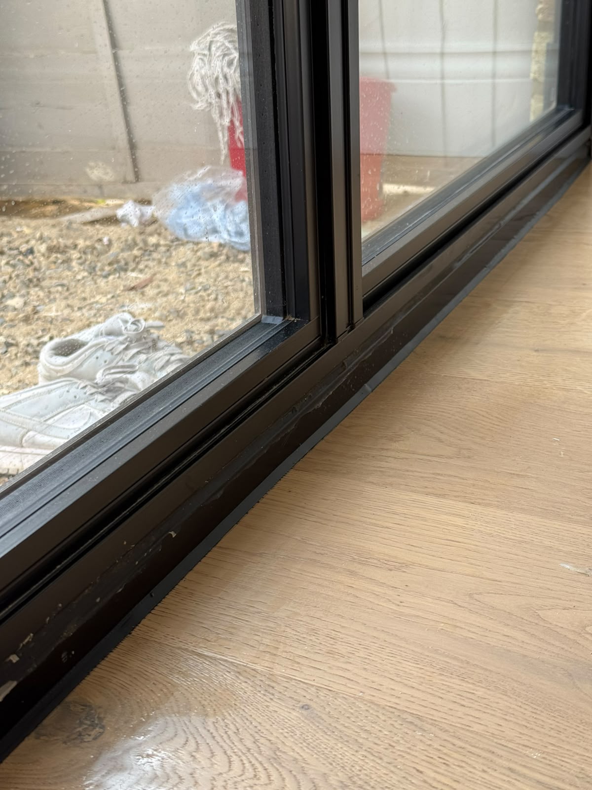 Black sliding door frame and threshold sealed by Blackline Mastic